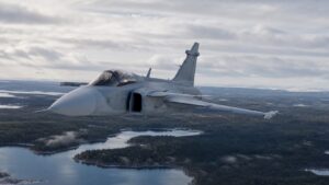 北欧の森林と湖上空を飛行するJAS 39グリペン級戦闘機