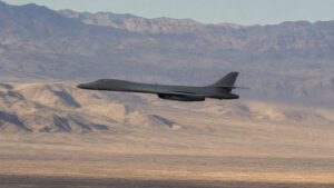 砂漠の山岳地帯を低空飛行するB-1B級可変翼爆撃機