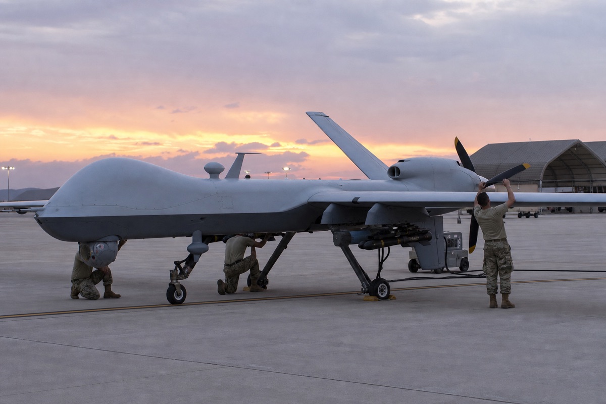 基地でセンサーと翼下搭載部を点検されるMQ-9級航空機