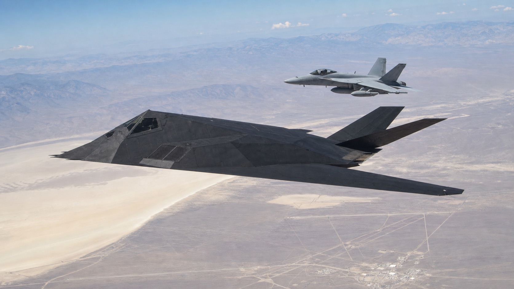 現代戦闘機とともに砂漠試験空域を飛行するF-117級機