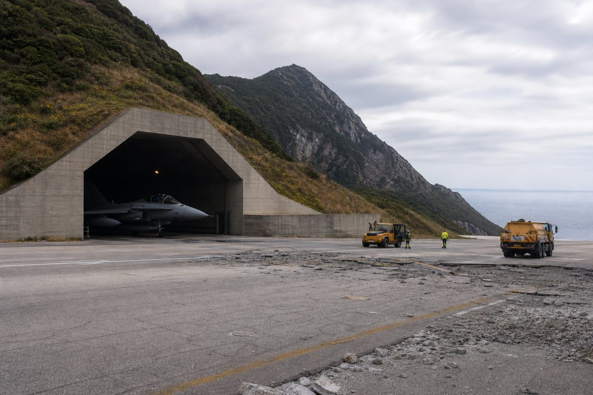 強化格納庫と滑走路復旧車両を備えた沿岸航空基地を描いた編集用イメージ
