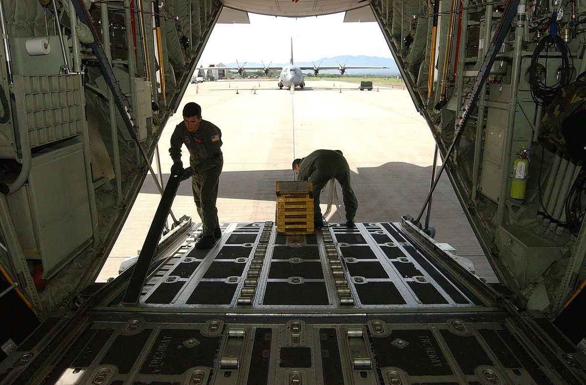貨物床のローラーと搭載作業を確認するC-17の乗員