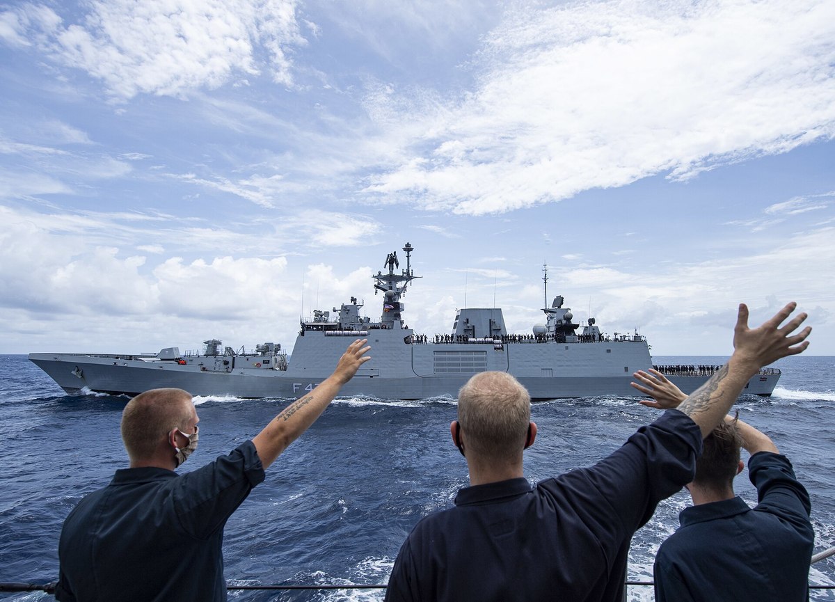米海軍の乗員が手を振る先を航行するフリゲート「シヴァリク」