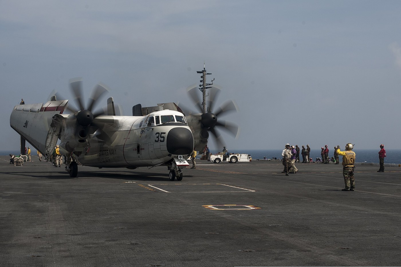 空母甲板でC-2Aを誘導する黄色のシャツの乗員。
